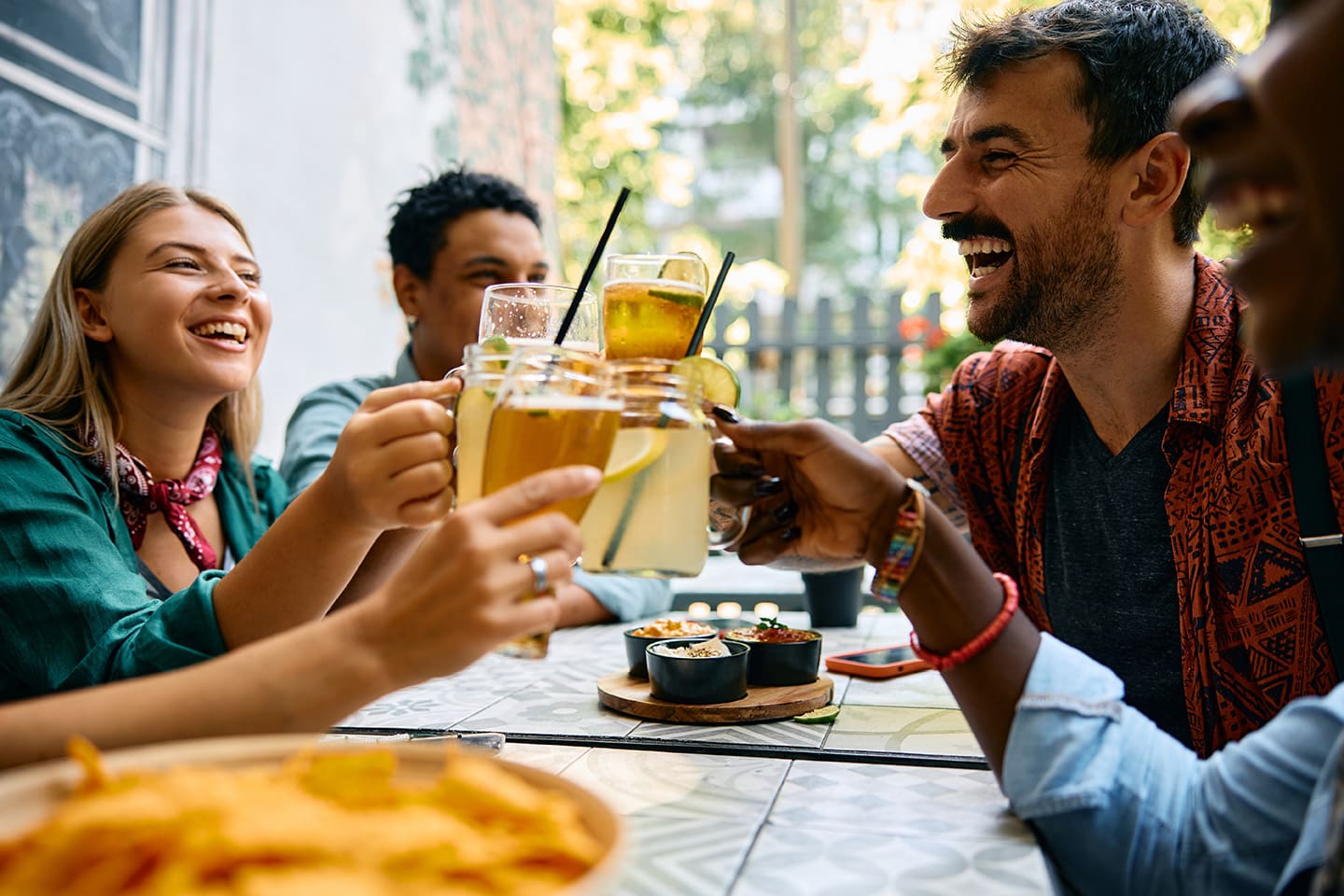 Group of happy friends having fun and toasting with drinks in cafe