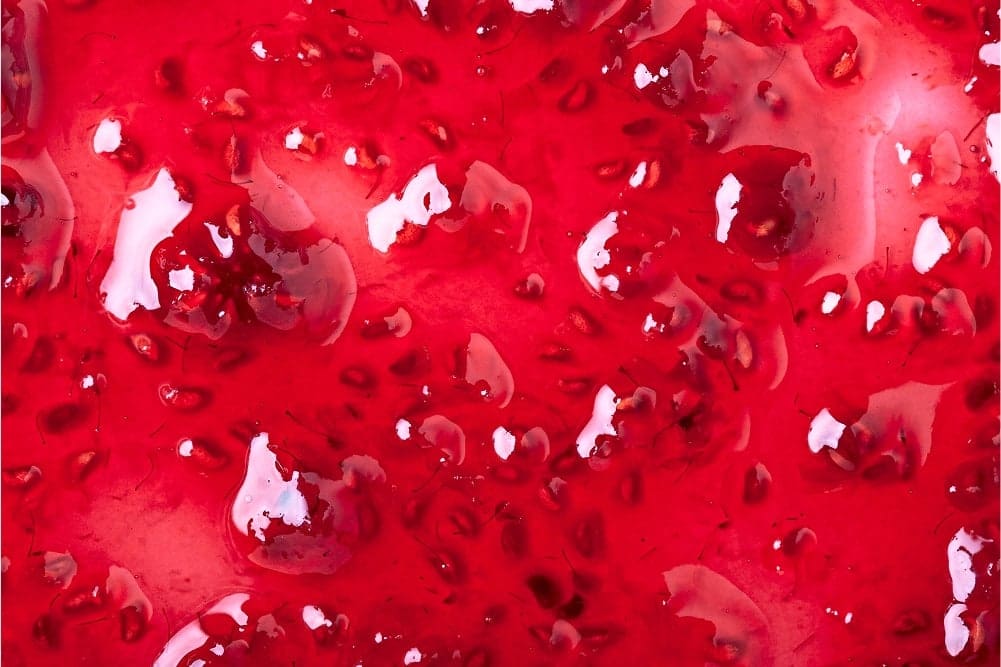 Close-up of glossy red strawberry jam with visible seeds and chunks.