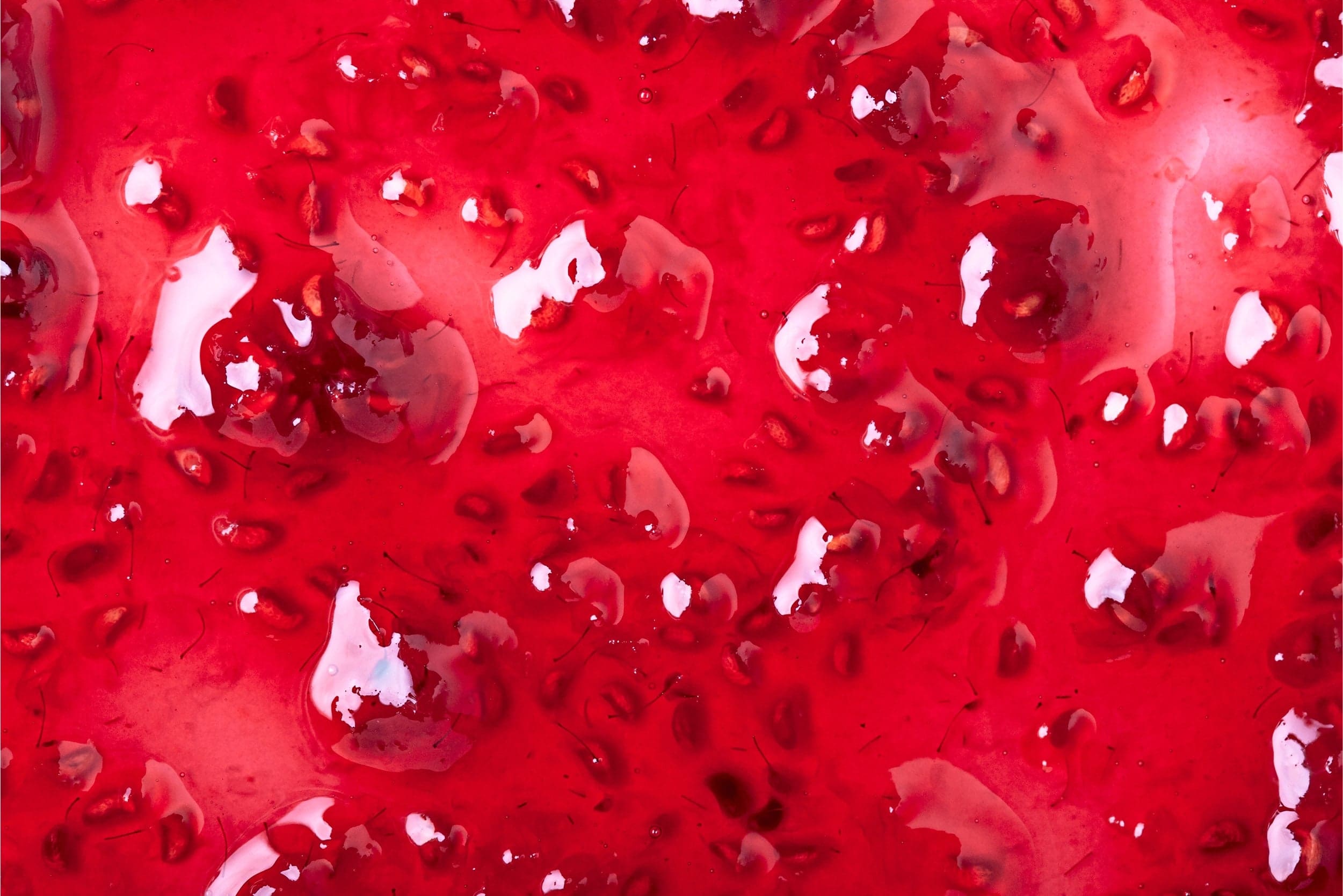 Close-up of glossy red strawberry jam with visible seeds and chunks.