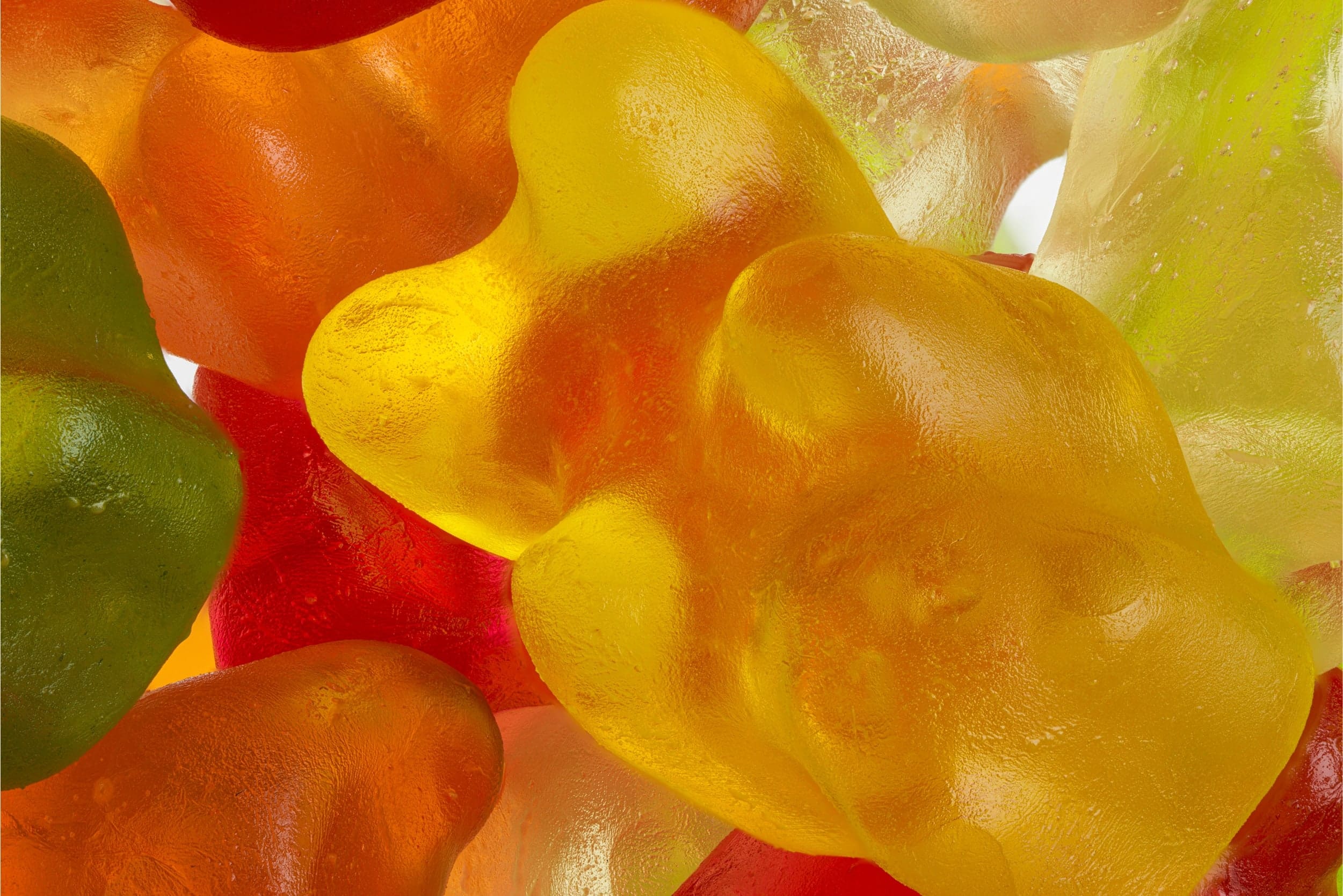 Close-up of assorted colourful gummy bears in red, orange, yellow, and green.